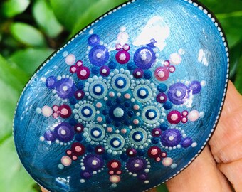 Mandala dot rock painting on natural stone in turquoise, purple, pink and blue with white accents on oval stone