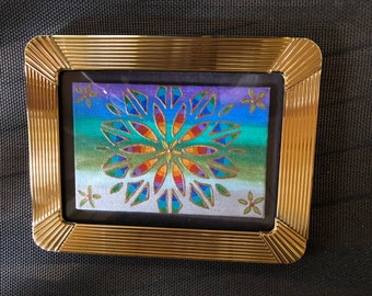 Painted rainbow mandala framed in a solid brass frame for tabletop or desktop.