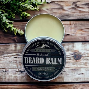 May include: A black and white label with the text "KECHI BATH CO. St. Benedict's BEARD BALM Sulraco Fresh (2oz / 56g)" on a silver tin container.