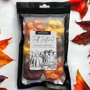 May include: A black package containing shower steamers wrapped in orange and gold foil. The label reads "Fall Festival" with illustrations of pumpkins and a basket of fruit. The package weighs 8 oz (230g).