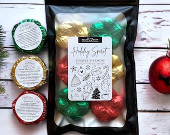 May include: A black package containing shower steamers wrapped in red, green, and gold foil. The package has a label that reads "Holiday Spirit" with festive illustrations. The package contains 8 oz (230g) of shower steamers.