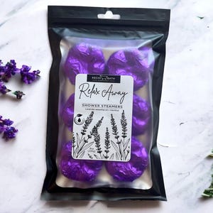May include: A black pouch with a clear front containing six purple shower steamers. The pouch has a white label that reads "Kechi Bath Company Relax Away Shower Steamers Lavender essential oil + menthol 8oz (230g)".