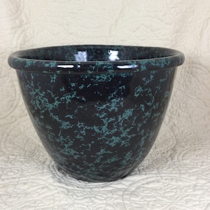 May include: A large, black ceramic bowl with a green marbled glaze. The bowl is round and has a wide rim.