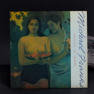 以下が含まれることがあります： 裸の上半身の女性がフルーツの入った皿を持っている、2人の女性の絵。絵のタイトルは「Objects of Desire」で、マイケル・フランティによる作品です。