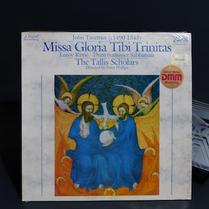 May include: A vinyl record album cover featuring the title "Missa Gloria Tibi Trinitas" by John Taverner. The cover art depicts two figures in blue robes with a dove and a globe, set against a gold and blue background. The album is a digital recording.