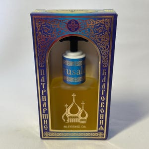 May include: A rectangular box with a blue and gold design, containing a bottle of Blessing Oil. The bottle has a black top and a blue and white label that says "Jerusalem". The box has text in a foreign language.