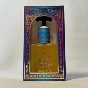 May include: A bottle of Blessing Oil in a decorative box. The bottle has a gold label with a church illustration and the words "Blessing Oil." The box is blue with gold accents and text in a foreign language.
