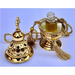 May include: Gold-toned metal censer with a small bottle of oil inside. The censer has a tassel and a chain for hanging.
