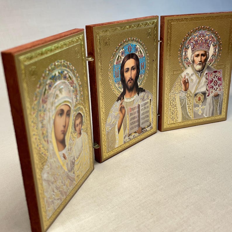 K&ouml;nnte beinhalten: Ein Triptychon mit religi&ouml;sen Ikonen in goldenen Rahmen. Das linke Feld zeigt eine Darstellung der Jungfrau Maria und des Kindes, das mittlere Feld zeigt Jesus Christus und das rechte Feld zeigt einen Heiligen mit einer Krone und einem Buch.