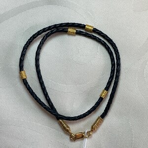 May include: A black leather cord necklace with gold accents. The cord is braided and has a clasp closure.