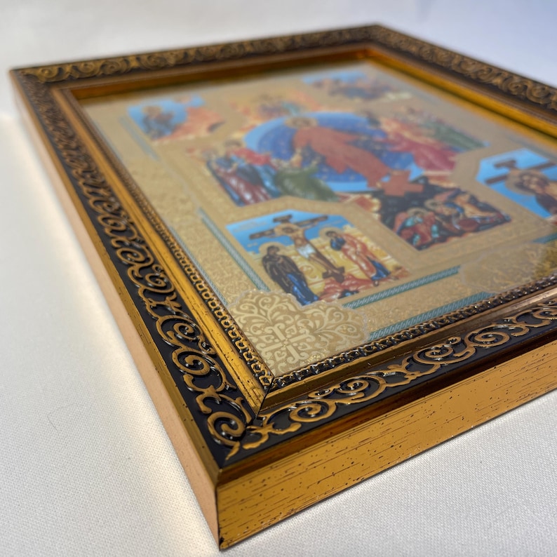 May include: A framed religious icon with a gold and black ornate border. The artwork depicts biblical scenes with figures in various colors, including red, blue, and gold. The frame has a detailed, decorative design.