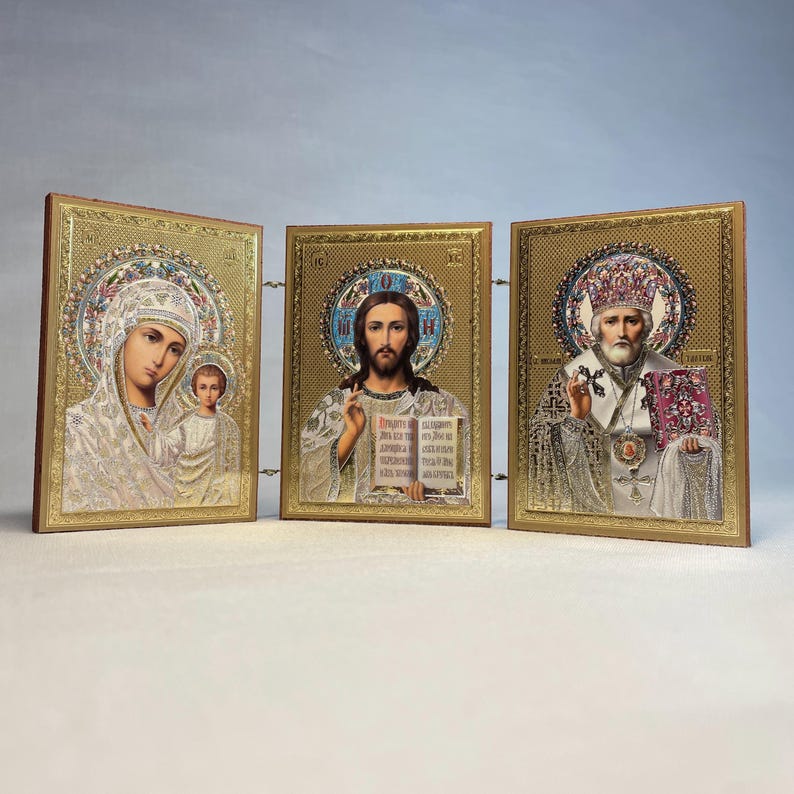 K&ouml;nnte beinhalten: Ein Satz von drei goldgerahmten religi&ouml;sen Ikonen. Die Ikonen zeigen die Jungfrau Maria und das Kind, Jesus Christus und den Heiligen Nikolaus. Die Ikonen sind in Gold gerahmt und haben einen dekorativen Rahmen.