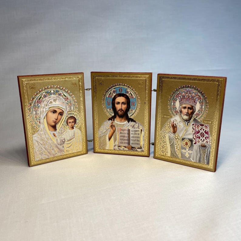 K&ouml;nnte beinhalten: Ein Satz von drei goldgerahmten religi&ouml;sen Ikonen. Die Ikonen zeigen die Jungfrau Maria und das Kind, Jesus Christus und einen Heiligen. Die Ikonen sind in Gold gerahmt und haben einen dekorativen Rand.
