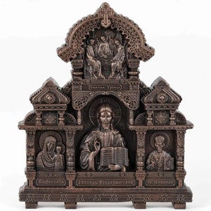 May include: A bronze-coloured icon depicting three religious figures in ornate frames. The top frame features the Holy Trinity, the middle frame shows Jesus holding a book, and the bottom frame shows a figure with a halo. The icon is decorated with intricate carvings and the text "СВЯТАЯ ТРОИЦА", "ГОСПОДЬ ВСЕДЕРЖИТЕЛЬ", "СВ. НИКОЛАЙ", and "КАЗАНСКАЯ" is visible.