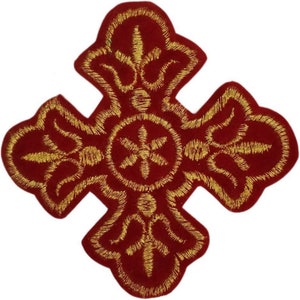 Puede incluir: Cruz de terciopelo rojo con bordado dorado. La cruz tiene un diseño decorativo con un círculo central y cuatro puntos.