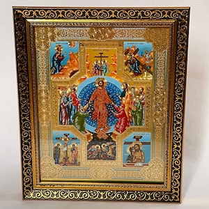 May include: A framed religious icon with a gold and black ornate border. The icon features a central image of a figure in red robes surrounded by other figures. The background includes blue and gold accents, with additional religious scenes depicted.