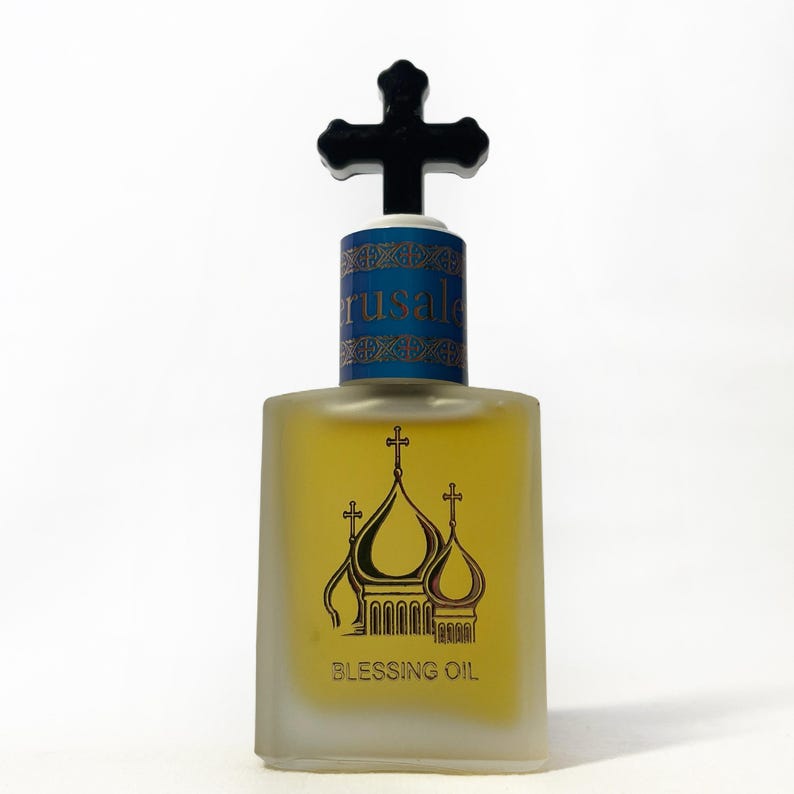 May include: A square glass bottle of Blessing Oil with a black cross-shaped stopper. The bottle has a blue and gold label with the word "Jerusalem" and a gold illustration of a church with the words "Blessing Oil".