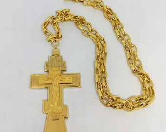 May include: A gold-toned cross pendant with intricate details and a matching gold chain. The cross features a depiction of Jesus Christ on the front.