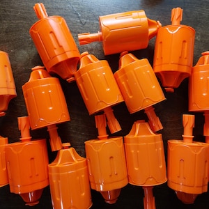 Op de afbeelding: Een groep van 14 oranje plastic speelgoedblasters met een uniek ontwerp. De blasters zijn allemaal scherp en willekeurig gerangschikt.