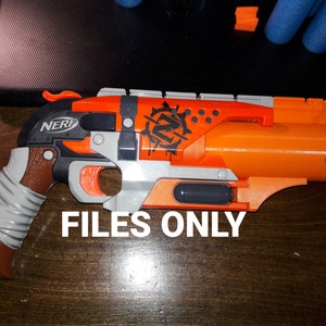 Op de afbeelding: Een oranje en grijze Nerf-pistool met een zwart-witte schedel en gekruiste beenderen ontwerp. Het pistool heeft een bruine grip en een zwarte loop. De tekst "NERF" is gedrukt op de zijkant van het pistool.