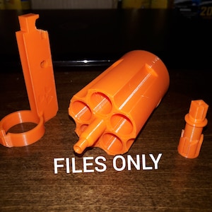 May include: A set of orange 3D printed parts for a toy gun. The set includes a cylinder with six barrels, a handle, and a small piece.