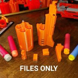 May include: A set of 3D printed orange plastic parts for a toy gun. The parts include a cylinder, a barrel, a handle, and a few smaller pieces. The text "FILES ONLY" is printed on a white piece of paper below the parts.