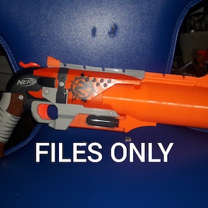 Op de afbeelding: Oranje en zwarte Nerf speelgoedpistool met een bruine handgreep en een zilveren loop. Het pistool heeft een zwart-wit ontwerp aan de zijkant met het woord "NERF" erop gedrukt.