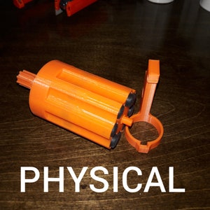 May include: An orange plastic 3D printed object with a gear on one end and a series of holes on the other. The object is open and has a separate orange plastic piece attached to it.
