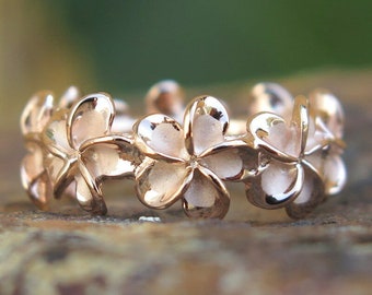 May include: A rose gold ring with a design of five plumeria flowers.