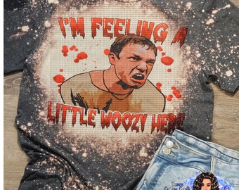Może przedstawiać: Szary t-shirt z wzorem rozpryskanym wybielaczem. Na koszulce znajduje się kreskówkowa ilustracja mężczyzny z tekstem "I'm feeling a little woozy here".