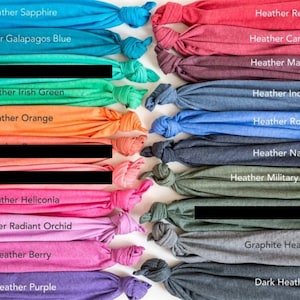 Peut inclure: Un ensemble d'&eacute;chantillons de tissu pli&eacute;s dans diff&eacute;rentes nuances de bleu, vert, rouge, orange, violet et gris. Chaque &eacute;chantillon porte une &eacute;tiquette avec le nom de la couleur, comme "Heather Sapphire", "Heather Galapagos Blue", "Heather Irish Green" et "Heather Orange".