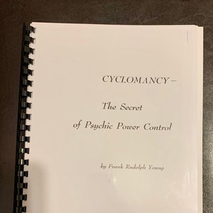 Może przedstawiać: Książka w spiralnej oprawie z białą okładką. Tytuł "CYCLOMANCY - The Secret of Psychic Power Control" jest wydrukowany w kolorze czarnym. Nazwisko autora, Frank Rudolph Young, znajduje się na dole.
