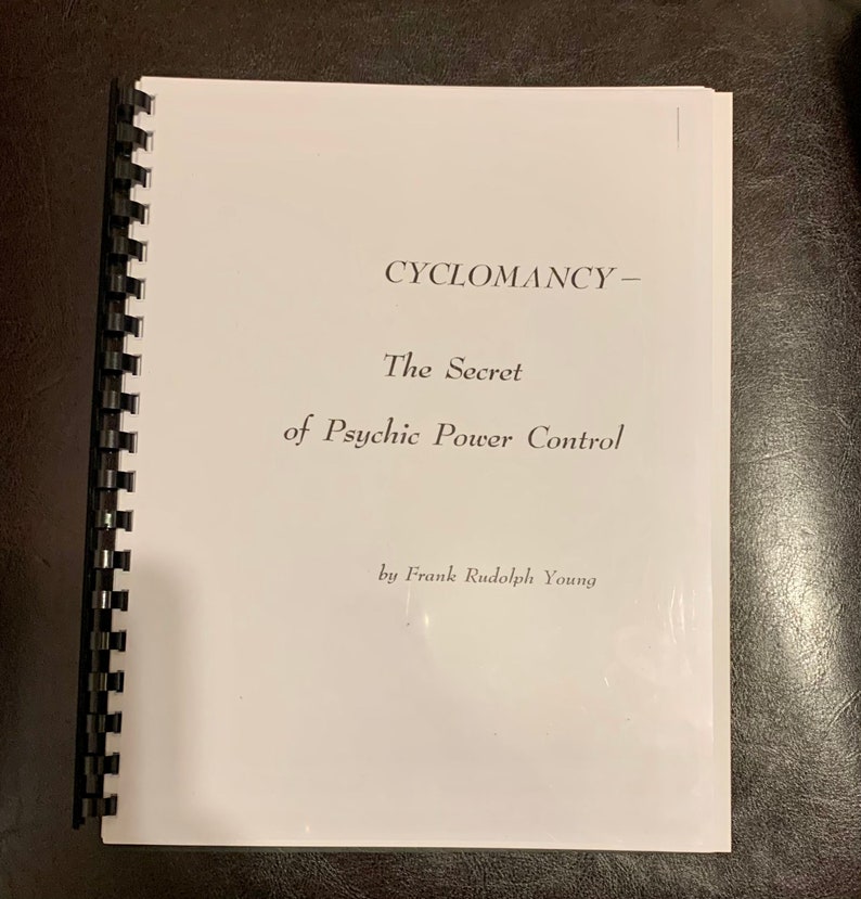 Może przedstawiać: Książka w spiralnej oprawie z białą okładką. Tytuł "CYCLOMANCY - The Secret of Psychic Power Control" jest wydrukowany w kolorze czarnym. Nazwisko autora, Frank Rudolph Young, znajduje się na dole.