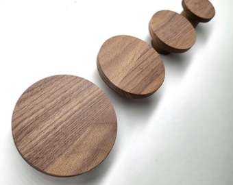 May include: Set of four round wooden knobs in various sizes. The knobs are made of dark brown wood with a natural grain pattern.
