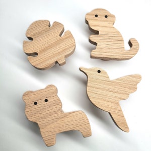 以下が含まれることがあります： 鳥、サル、クマ、モンステラの葉の形をした木製の壁掛けフック4つ。フックは薄い茶色の木でできており、黒く塗られた目があります。