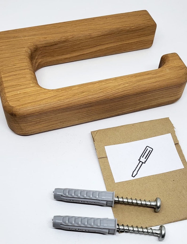 May include: A wooden toilet paper holder with a rectangular design. The holder is made of light brown wood and includes mounting hardware: screws and wall anchors. A small card with a screwdriver illustration is also included.