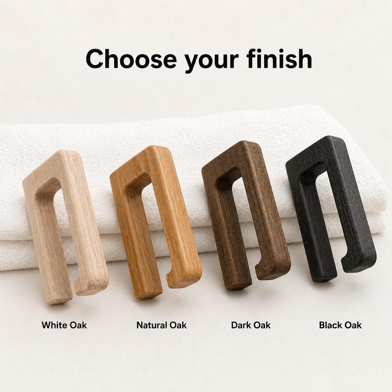 May include: Four wooden towel hooks in white oak, natural oak, dark oak, and black oak finishes. The hooks are rectangular with a curved handle. Text above reads "Choose your finish".