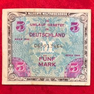 May include: A vintage five Mark banknote from Germany, featuring the text "ALLIIERTE MILITÄRBEHÖRDE" and "FÜNF MARK". The note has a blue and purple design with the number 5 in each corner and a central serial number.