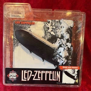 May include: A clear plastic display case with a black and white image of a blimp. The image is from the Led Zeppelin album cover for "Houses of the Holy". The text "Led Zeppelin" is printed in black on a white background below the image. The text "Brand New Product" is printed in red on a white background in the bottom right corner of the image.