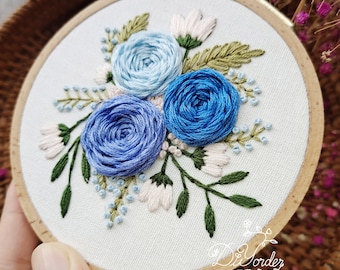 May include: Embroidered hoop art featuring a floral design with blue, light blue, and white flowers on a white background. The hoop is made of wood and has a natural finish.
