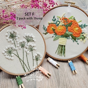 Peut inclure: Deux cerceaux &agrave; broder avec des motifs floraux. Le cerceau de gauche pr&eacute;sente une fleur blanche avec des tiges vertes. Le cerceau de droite pr&eacute;sente un bouquet de fleurs orange avec des feuilles et des tiges vertes. Le texte "SET F 2 pack with 1 hoop" est visible au-dessus des cerceaux.