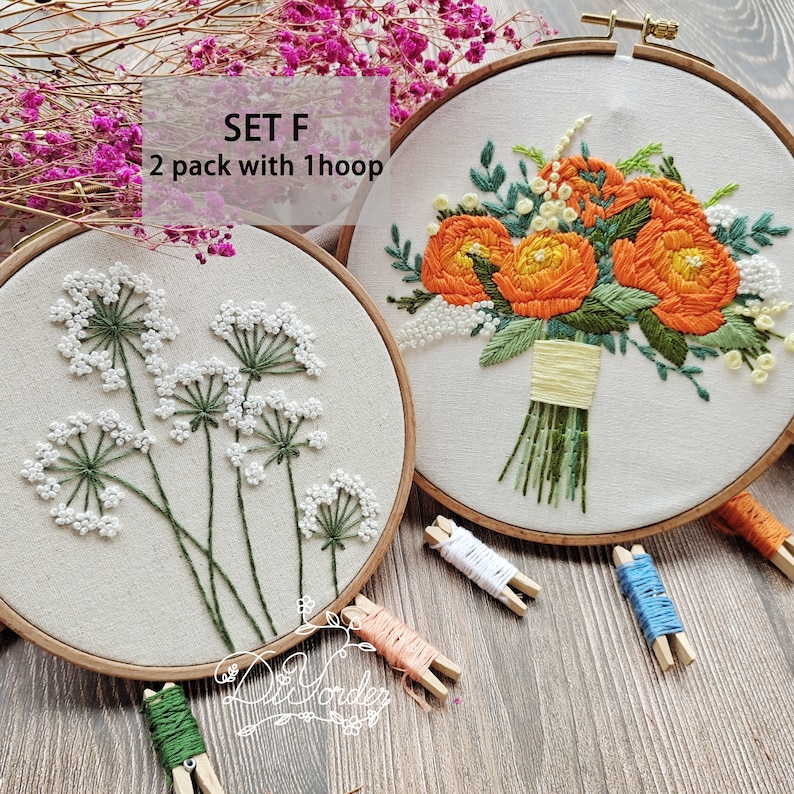 Peut inclure: Deux cerceaux &agrave; broder avec des motifs floraux. Le cerceau de gauche pr&eacute;sente une fleur blanche avec des tiges vertes. Le cerceau de droite pr&eacute;sente un bouquet de fleurs orange avec des feuilles et des tiges vertes. Le texte "SET F 2 pack with 1 hoop" est visible au-dessus des cerceaux.