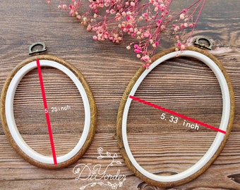 May include: Two embroidery hoops with wooden frames and white inner rings. The larger hoop measures 5.33 inches in diameter and the smaller hoop measures 5.25 inches in diameter.