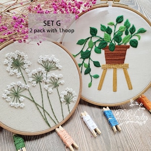 Peut inclure: Deux ensembles de cerceaux &agrave; broder, l'un avec un motif de fleurs blanches et l'autre avec une plante verte dans un pot brun sur un support en bois. Le texte "SET G 2 pack with 1 hoop" est visible en haut de l'image.