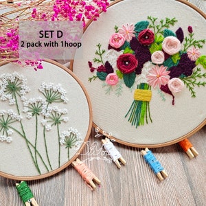 Peut inclure: Ensemble de deux cerceaux &agrave; broder avec des motifs floraux. Un cerceau pr&eacute;sente un bouquet de fleurs roses, rouges et violettes. L'autre cerceau pr&eacute;sente un motif de fleurs blanches avec des tiges vertes. Le texte "SET D 2 pack with 1 hoop" est visible sur l'image.