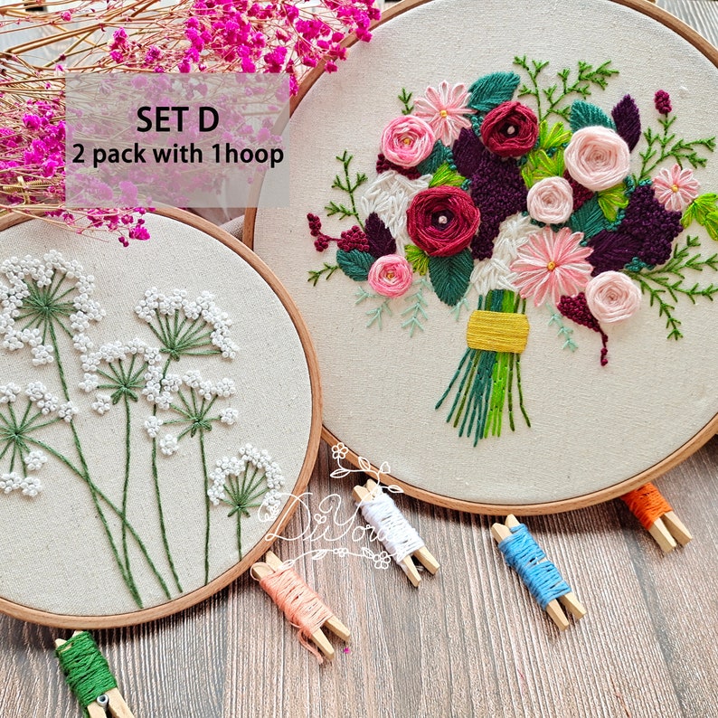 Peut inclure: Ensemble de deux cerceaux &agrave; broder avec des motifs floraux. Un cerceau pr&eacute;sente un bouquet de fleurs roses, rouges et violettes. L'autre cerceau pr&eacute;sente un motif de fleurs blanches avec des tiges vertes. Le texte "SET D 2 pack with 1 hoop" est visible sur l'image.