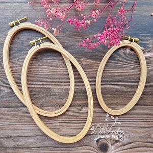 May include: Three wooden embroidery hoops of different sizes, with a natural wood finish and brass screw closures. The hoops are arranged on a wooden surface.