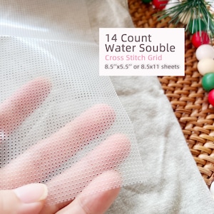 May include: A translucent 14 count water soluble cross stitch grid sheet with a perforated pattern. The text on the image reads 14 Count Water Souble Cross Stitch Grid 8.5"x5.5" or 8.5x11 sheets. The material is flexible and semi-transparent.