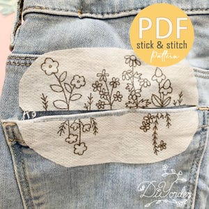 Peut inclure: Jean bleu clair avec un motif floral à coller et à coudre sur la poche arrière. Le motif présente diverses fleurs et feuillages dans un style délicat, dessiné à la main. Le texte "PDF stick & stitch Pattern" est dans un cercle jaune.