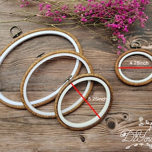 May include: Three oval embroidery hoops with wooden frames and white inner rings. The hoops measure 4.25 inches, 5.25 inches, and 7 inches in diameter.